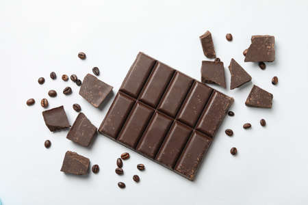 Chocolate bar and coffee seeds on white background