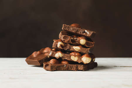 Tasty chocolate pieces on white wooden table