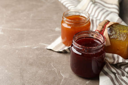 Napkin and glass jars with jam on gray background, space for textの写真素材