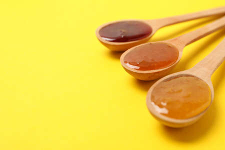 Spoons with jam on yellow background, space for textの写真素材