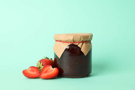 Delicious strawberry jam on mint background, space for text