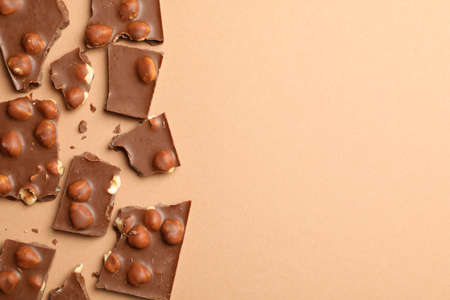 Chocolate pieces on beige background, top view. Sweet food