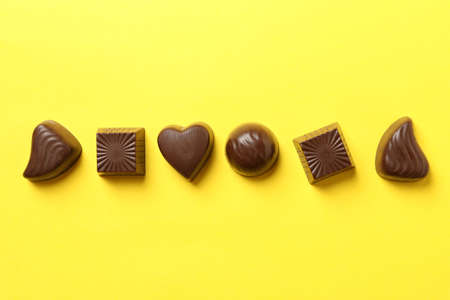 Tasty chocolate candies on yellow background, top viewの写真素材