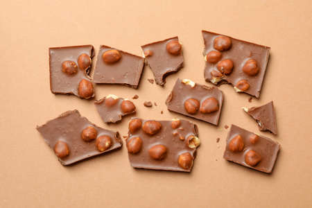 Chocolate pieces on beige background, top view. Sweet food