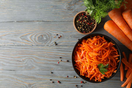 Composition with tasty carrot salad on wooden background. Korean carrot