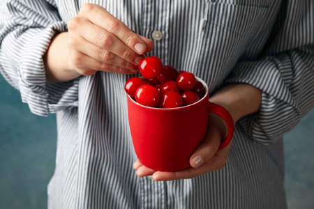 Woman holds cup with fresh red cherry, close upの写真素材