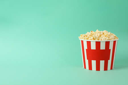 Cardboard bucket with tasty popcorn on mint backgroundの写真素材