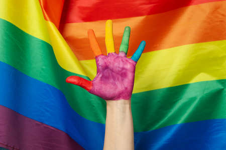 Female hand with LGBT colors against LGBT flag