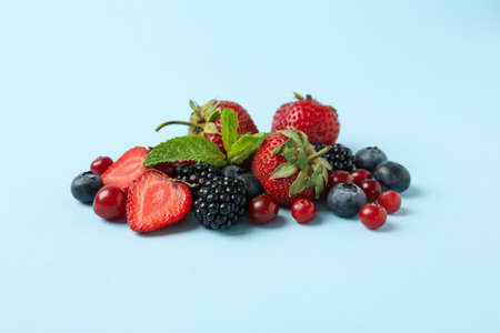 Mix of fresh berries on blue background, space for text