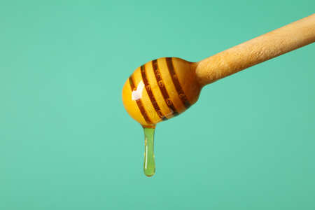 Wooden dipper with honey on mint background, close upの写真素材