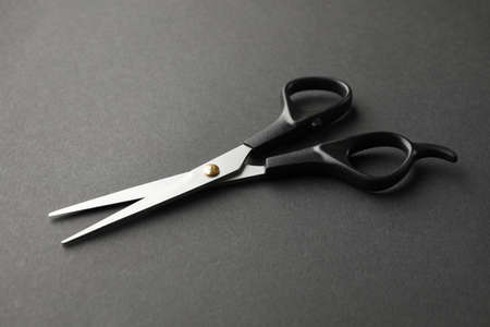 Black hairdresser scissors on black background, space for text