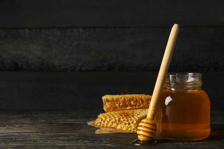 Honeycombs, jar with honey and dipper on wooden background