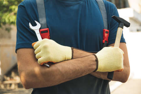 Man in overalls holds construction tools outdoorの写真素材