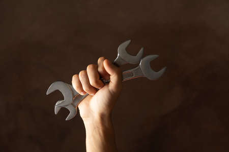 Male hand holds wrenches on brown background