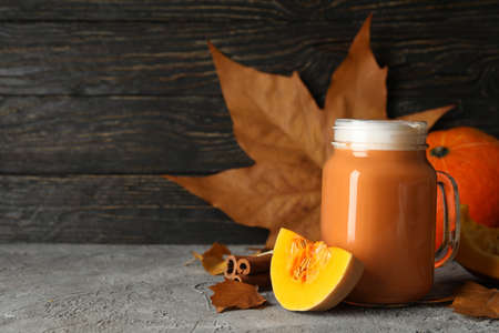 Composition with pumpkin latte, pumpkin, leaves and cinnamon on gray tableの写真素材