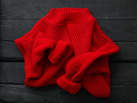 Red knitted sweater on wooden background, top viewの写真素材