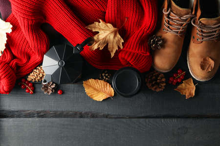 Autumn concept with sweater, coffee and boots on wooden tableの写真素材