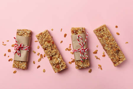 Tasty granola bars on pink background, top view