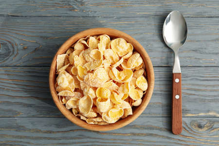 Spoon and bowl of muesli on wooden backgroundの写真素材
