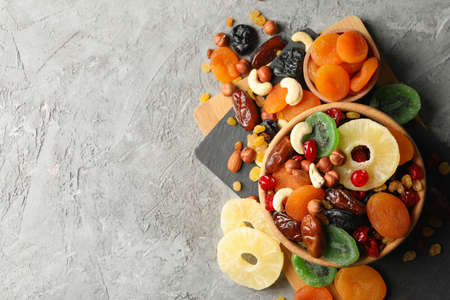 Board and bowls with dried fruits and nuts on gray backgroundの写真素材
