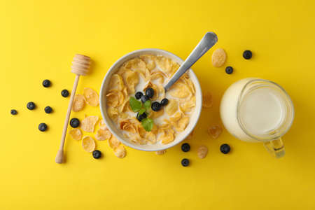 Milk, bowl of muesli and dipper on yellow backgroundの写真素材