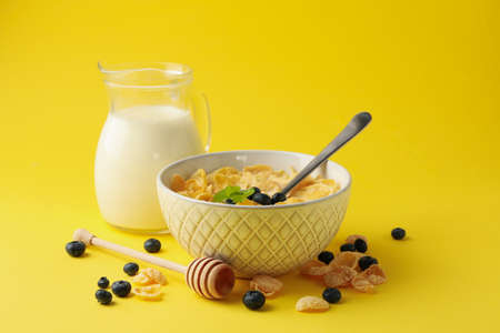 Milk, bowl of muesli and dipper on yellow backgroundの写真素材