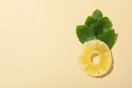 Dried pineapple and leaves on beige background, space for text