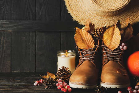 Concept of autumn wear with boots and leaves on wooden background