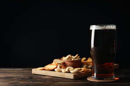 Glass of beer and snacks on wooden tableの写真素材