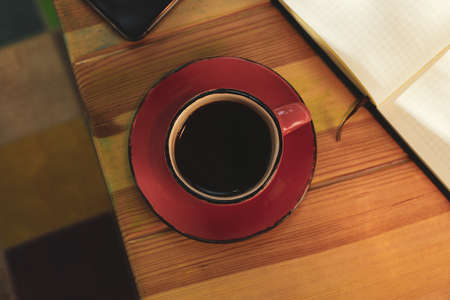 Cup of coffee, notebook and phone on wooden tableの写真素材