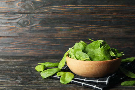 Wooden bowl with spinach and napkin on wooden backgroundの写真素材