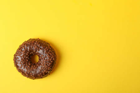 Tasty chocolate donut on yellow background, space for textの写真素材