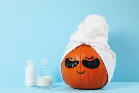 Skincare accessories and pumpkin with eye patches on blue backgroundの写真素材