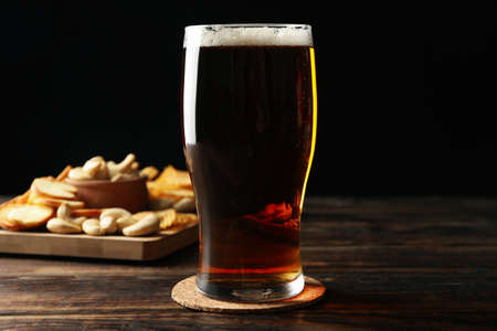 Glass of beer and snacks on wooden tableの写真素材
