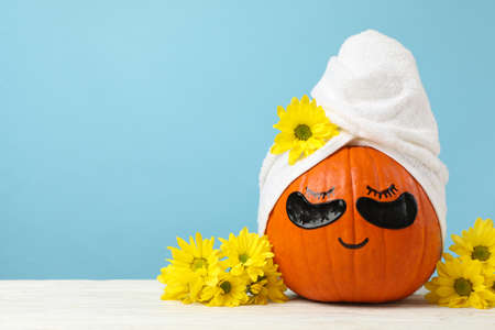 Pumpkin with towel, flowers and under eye patches against blue backgroundの写真素材