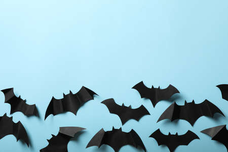 Paper bats on blue background, space for text