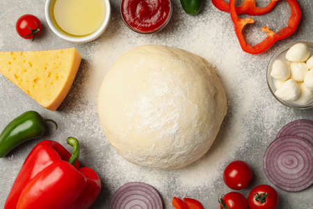 Dough and ingredients for cooking pizza on gray backgroundの写真素材