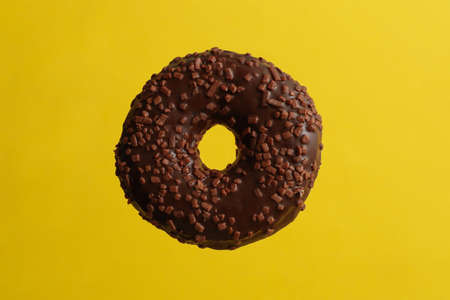 One tasty chocolate donut on yellow backgroundの写真素材