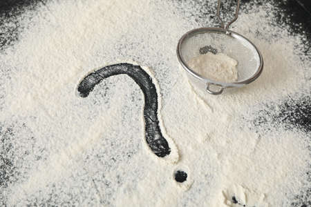 Flour, sieve and question mark on black backgroundの写真素材