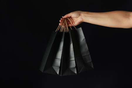 Female hand hold paper bags on black backgroundの写真素材