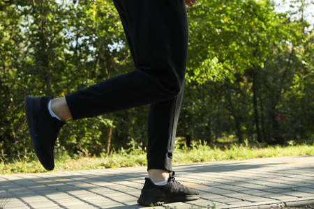 A man in a tracksuit running in the park in sunny morning