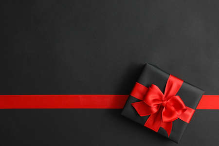 Gift box and red ribbon on black backgroundの写真素材