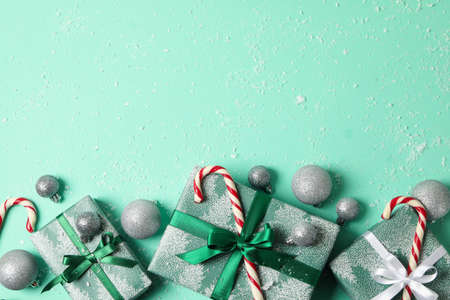 Gift boxes, candy cane and baubles on mint background with snowの写真素材