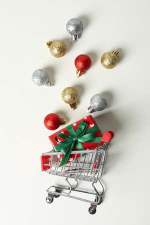 Shop cart with Christmas box and baubles on white backgroundの写真素材