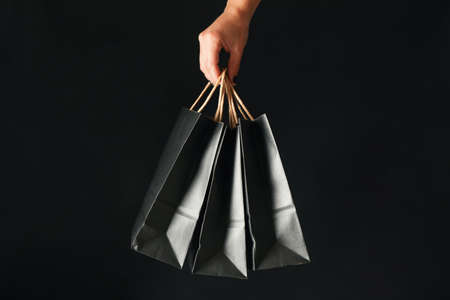Female hand hold paper bags on black backgroundの写真素材