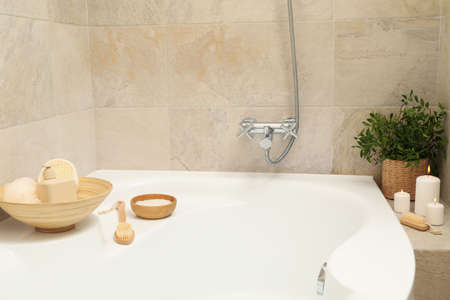 Bath with personal hygiene accessories in light beige bathroomの写真素材