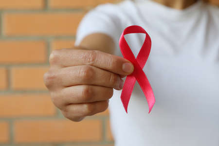 Woman with pink awareness ribbon against brick wall backgroundの写真素材