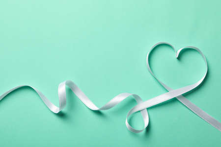 Heart made of white ribbon on mint backgroundの写真素材