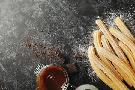 Concept of lunch with churros and chocolate on dark table