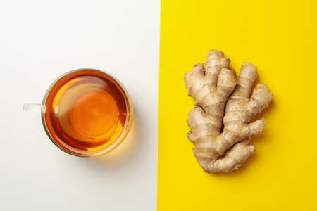 Fresh ginger and cup of tea on two tone background